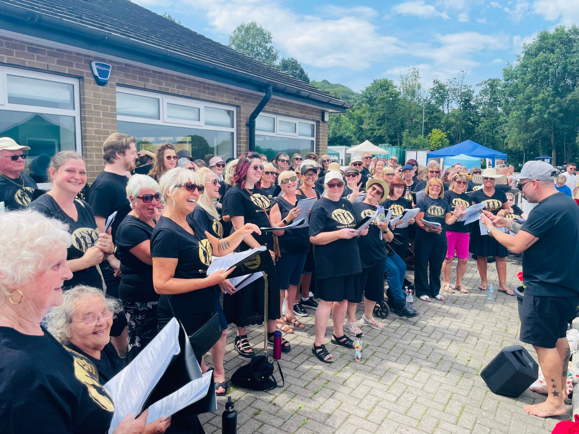 VOY members singing outdoors in the sunshine at a summer community event